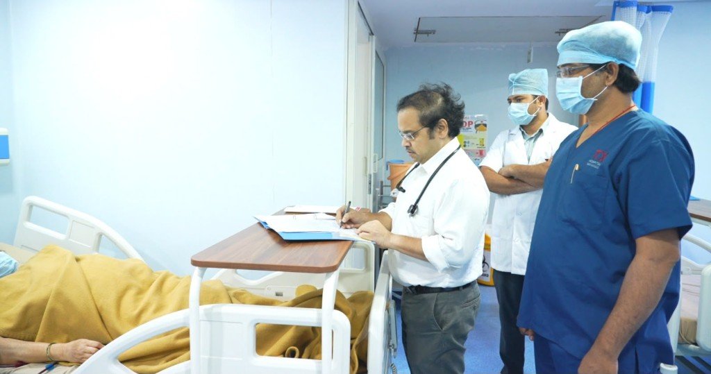 Doctor writing notes while medical staff observe patient care